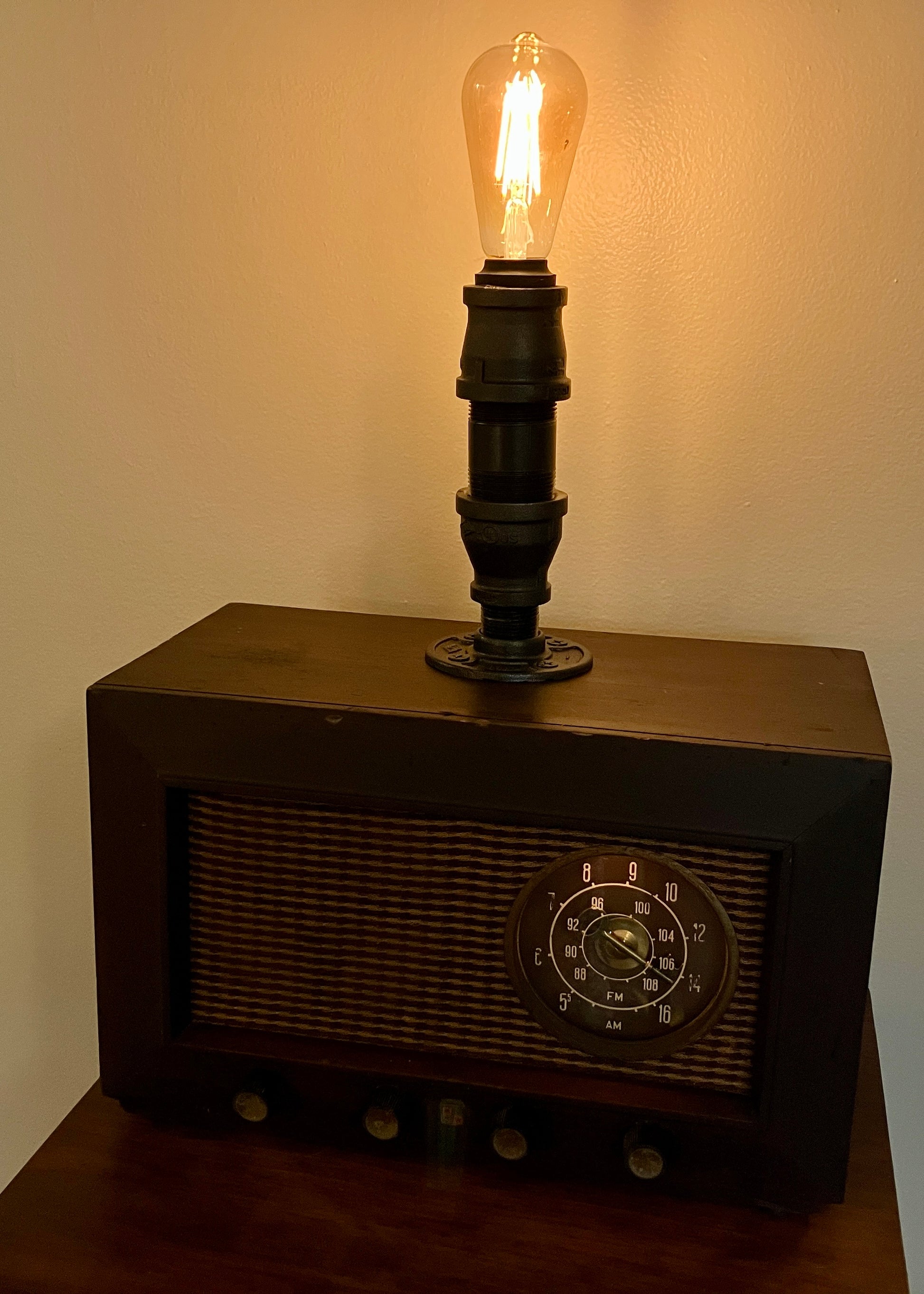 Picture of an antique tube radio turned into lamp with iron pipe and smart bulb